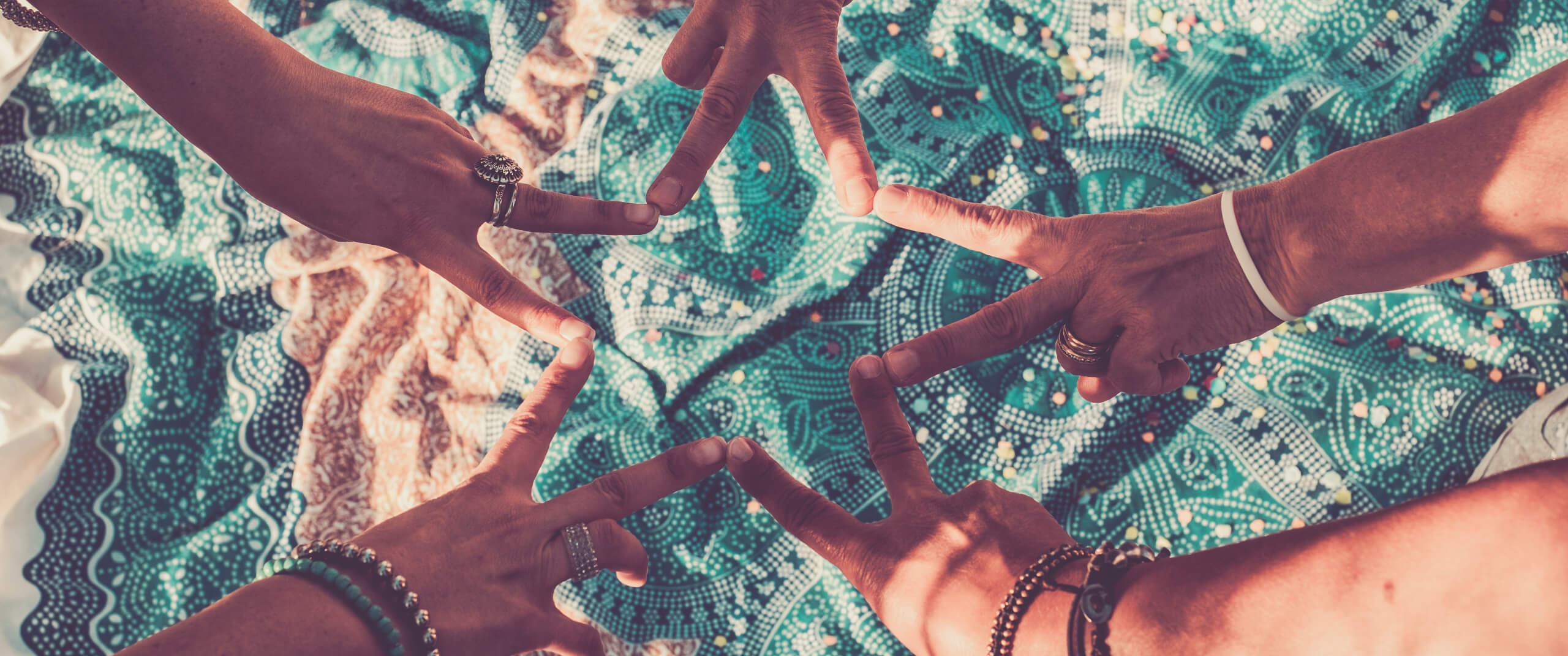 Five hands doing the peace sign in a circle, forming a star with their fingers
